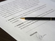 Close-up of a pen resting on a printed document with text and a visible signature line.